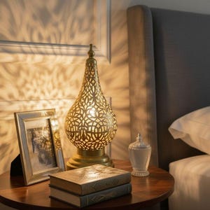 Handmade Moroccan brass lamp featuring intricate vintage detailing, perfect for antique bedside table decor or boho living spaces. This artisan-crafted brass light adds warm ambient glow and authentic Moroccan charm to any rustic or Arabic-inspired home. Ideal gift for lovers of unique, handcrafted lighting.