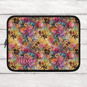 May include: Black laptop sleeve with a colorful floral and bee pattern. The design features yellow, pink, purple, and blue flowers with several bees. The name "Allison" is written in pink script.