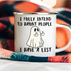 Puede incluir: Taza de esmalte blanco con borde y asa plateados. La taza presenta una ilustraci&oacute;n de fantasma de dibujos animados haciendo una peineta, con el texto "I FULLY INTEND TO HAUNT PEOPLE I HAVE A LIST."