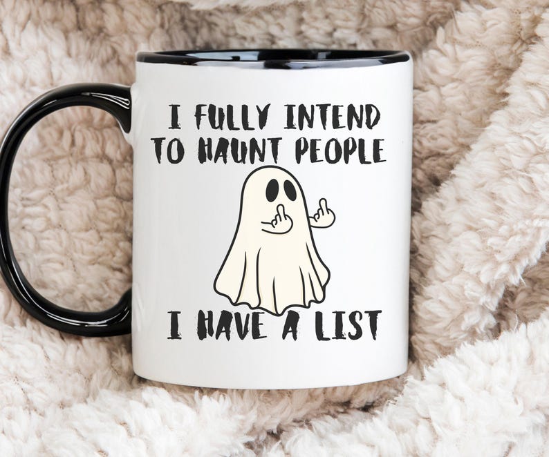 Puede incluir: Taza de cer&aacute;mica blanca con asa y borde negros. La taza presenta una ilustraci&oacute;n de fantasma de dibujos animados con el texto "I FULLY INTEND TO HAUNT PEOPLE I HAVE A LIST."