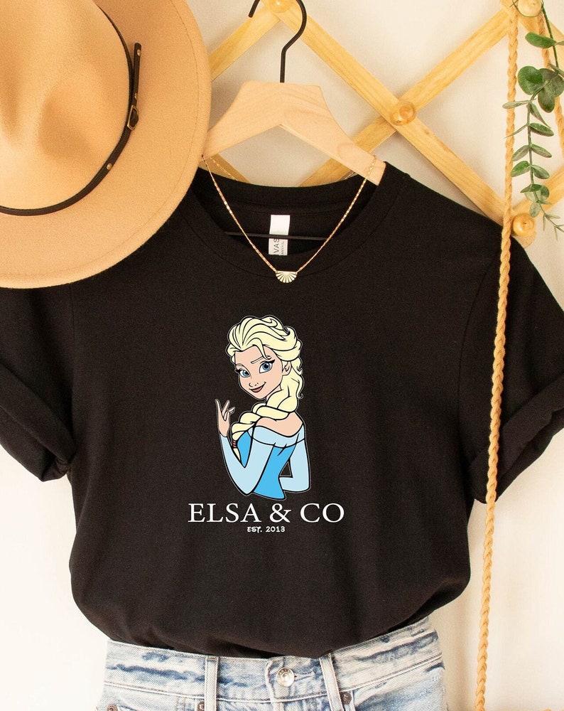 May include: Black t-shirt with a cartoon image of Elsa from Frozen. The text "Elsa & Co. Est. 2013" is printed below the image.