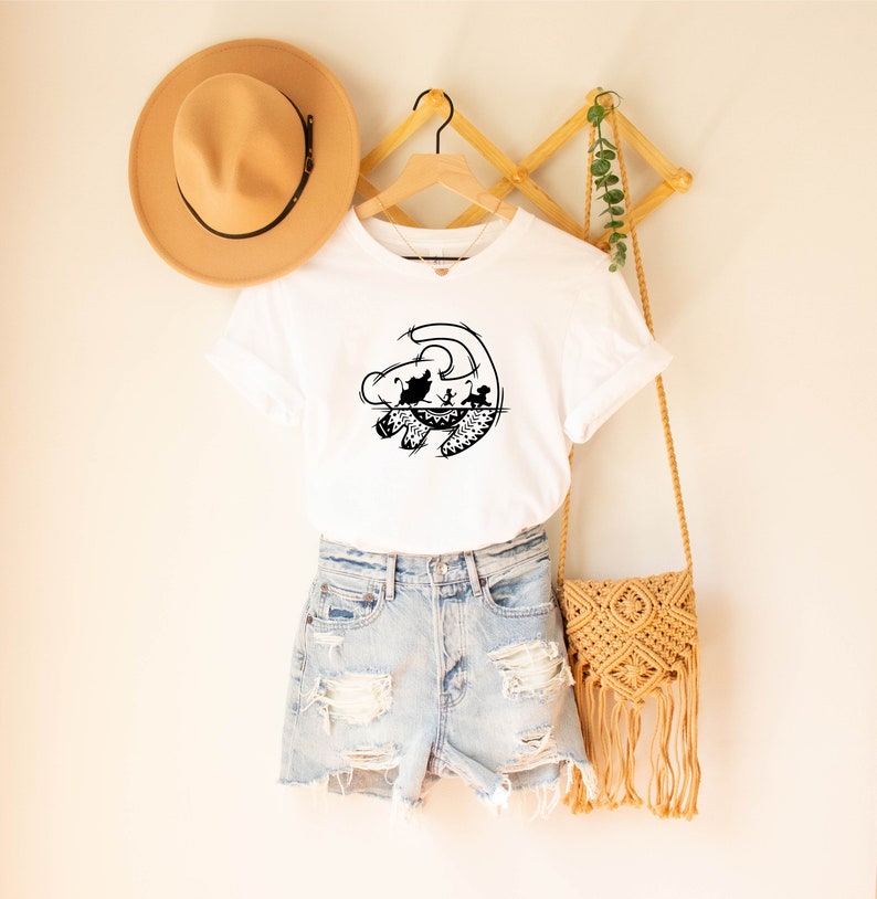 May include: White t-shirt with a black silhouette of Simba from The Lion King. The silhouette shows Simba as a cub with his parents Mufasa and Sarabi.