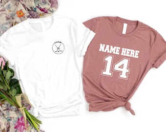 May include: Two white t-shirts, one with a black circle and crossed hockey sticks with the text "Team Name" inside the circle, and the other with the text "NAME HERE 14" in white.
