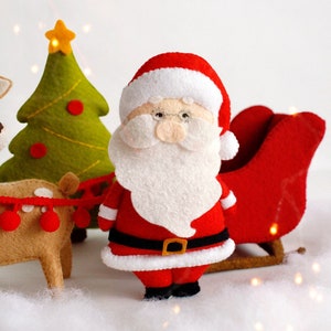Felt toys - Santa Claus standing near the sleigh, reindeer Rudolph and Christmas tree on the "snow"