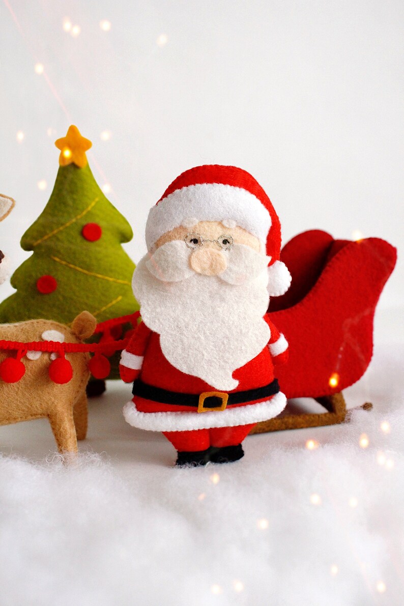 Felt toys - Santa Claus standing near the sleigh, reindeer Rudolph and Christmas tree on the "snow"