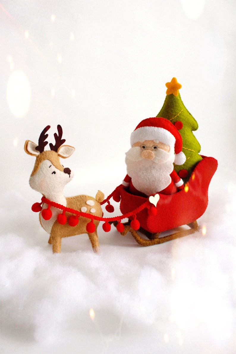 Felt Christmas toys - Santa Claus standing near the sleigh, reindeer Rudolph and Christmas tree on the snow