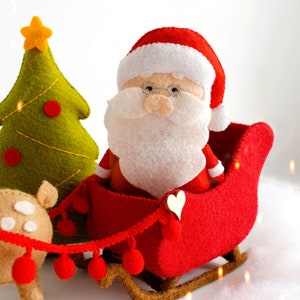 Felt toys - Santa Claus standing near the sleigh, reindeer Rudolph and Christmas tree on the snow, side view