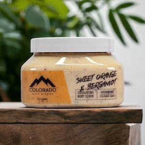 May include: A white jar with a yellow label containing a sweet orange and bergamot exfoliating body scrub. The label reads "Colorado Bath & Body" and "Sweet Orange & Bergamot". The jar is 8 oz (240 ml) and is made in Colorado.