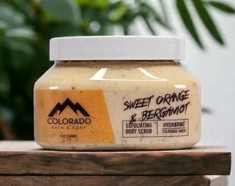 May include: A white jar with a yellow label containing a sweet orange and bergamot exfoliating body scrub. The label reads "Colorado Bath & Body" and "Sweet Orange & Bergamot". The jar is 8 oz (240 ml) and is made in Colorado.