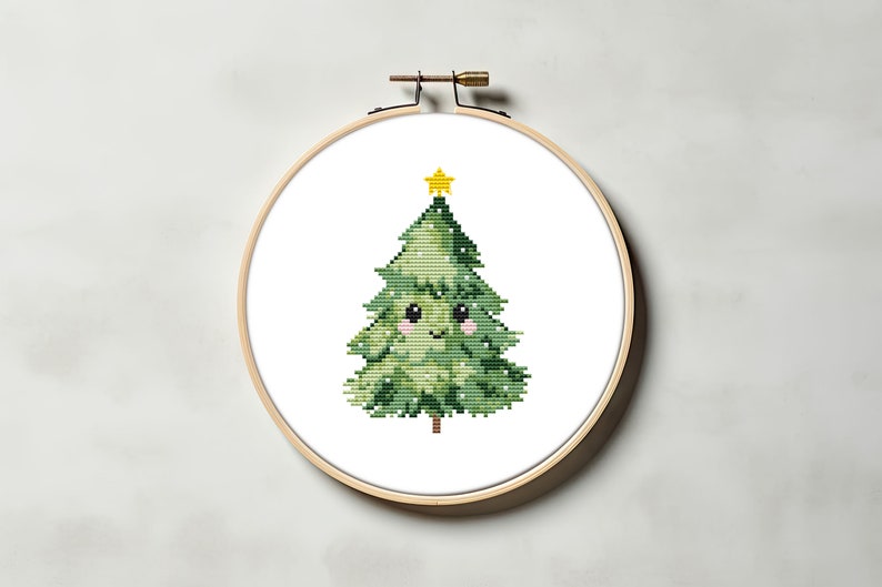 May include: A green cross-stitch Christmas tree with a yellow star on top and a smiling face. The tree is in a wooden embroidery hoop.