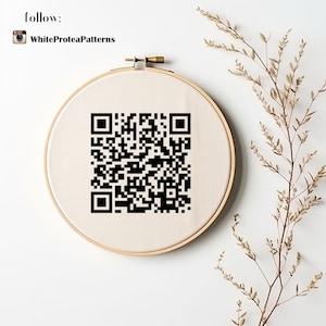 May include: A round embroidery hoop with a beige fabric featuring a black QR code. The hoop is set against a white background, with the text "follow:" and "WhiteProteaPatterns" at the top. Dried plant stems are on the right.