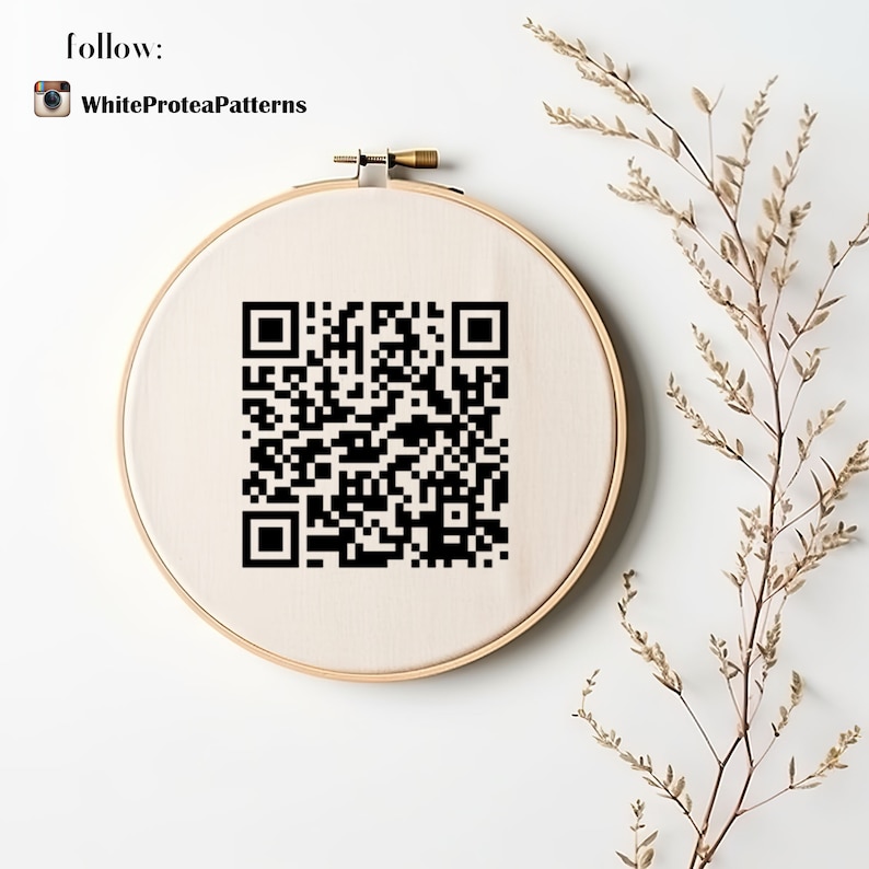 May include: A round embroidery hoop with a beige fabric featuring a black QR code. The hoop is set against a white background, with the text "follow:" and "WhiteProteaPatterns" at the top. Dried plant stems are on the right.