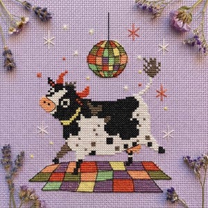 May include: Cross-stitch art featuring a dancing cow on a checkered dance floor, with a disco ball above. The cow is black and white with orange horns and a yellow collar. The background is lavender, with floral and star accents.