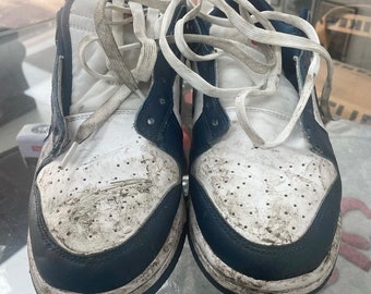May include: A pair of white and navy blue sneakers with white laces. The sneakers are dirty and have visible wear and tear.