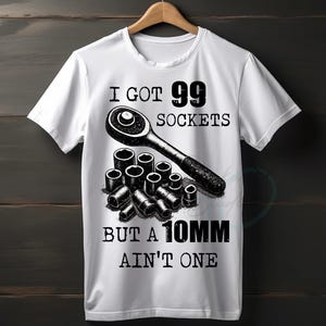 Könnte beinhalten: Weißes T-Shirt mit einer Grafik von Schraubenschlüssel und Steckschlüsseln. Der Text lautet "I GOT 99 SOCKETS BUT A 10MM AIN'T ONE". Das Design ist in Schwarz und Weiß.