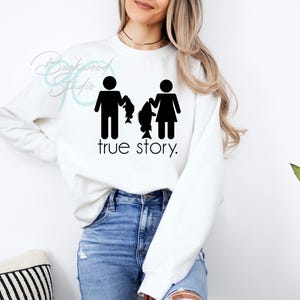 May include: White sweatshirt with a black graphic of a stick figure man holding a fish and a stick figure woman holding a fish. The text "true story." is below the graphic.