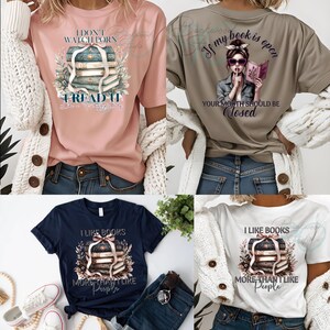 以下が含まれることがあります： 本をテーマにしたグラフィックが描かれた4枚のTシャツ。ピンクのシャツには「I DON'T WATCH PORN, READ IT」と書かれています。別のタンシャツには、本を読んでいる女性が描かれており、「If my book is open, your mouth should be closed」と書かれています。2枚のシャツには「I LIKE BOOKS MORE THAN I LIKE PEOPLE」と書かれています。