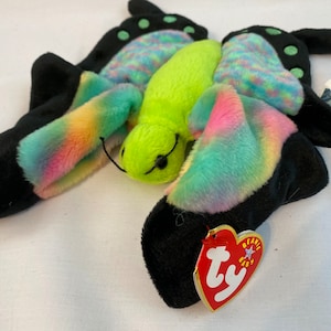 May include: A green and rainbow butterfly beanie baby with a black and white tag that reads "Beanie Baby" and "Ty".
