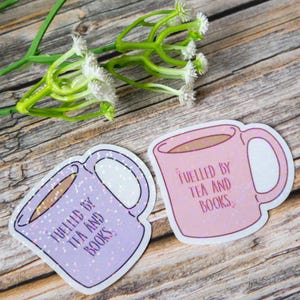 May include: Two coffee mug stickers with a glittery finish. One sticker is pink and says "Fuelled by tea and books". The other sticker is purple and says "Fuelled by tea and books".