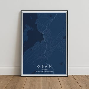 May include: A rectangular framed wall art print featuring a dark blue map of Oban, Scotland. The map displays white line work for roads and geographical features. The text reads OBAN, Scotland, and the coordinates 56°24'55" N / 05°28'18" W.