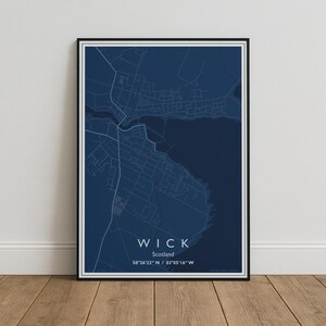 May include: A framed map print of Wick, Scotland, featuring a dark blue background with light blue street lines. The text reads WICK, Scotland, and the coordinates 58°26'23" N / 03°05'16" W. The print is enclosed in a thin black frame.