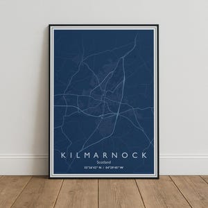 May include: A framed wall art print featuring a dark blue map of Kilmarnock, Scotland. The map displays white street lines and geographic features. Below the map, the text reads KILMARNOCK, Scotland, and the coordinates 55°36'42" N / 04°29'45" W.