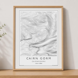 May include: A framed topographic map print featuring the Cairn Gorm mountain range in the Cairngorms. The artwork displays detailed black contour lines on a white background with the text CAIRN GORM, CAIRNGORMS, 1244m, and 4084ft.