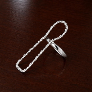 May include: A silver-toned ring featuring a smooth, circular band connected to a large, elongated, rectangular-shaped top piece. The rectangular component has a textured, wavy surface pattern that extends vertically above the finger band.
