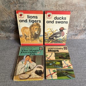 May include: Four vintage Ladybird books are shown, including "lions and tigers" and "ducks and swans." The books have red and white covers with illustrations of a lion, a duck, and other images. The titles are in bold, black text.