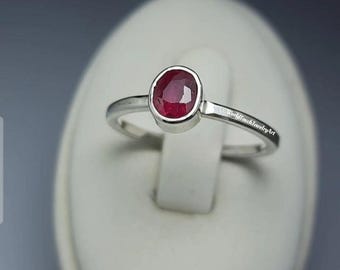 May include: A silver ring with a red oval gemstone. The ring is engraved with the text "WorldTouch Jewelry Art".