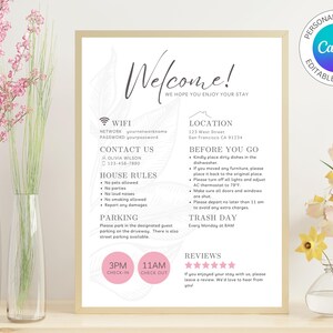 May include: A welcome sign with a floral design and information about WiFi, contact information, house rules, parking, location, before you go, trash day, reviews, and check-in/check-out times. The sign is printed on white paper with black text and pink accents.