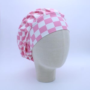 May include: Pink and white checkered surgical scrub hat. The hat is made of a soft, comfortable fabric and has a gathered top.