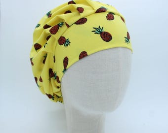 Könnte beinhalten: Ein gelber Stoffhut mit Ananasdruck. Der Hut ist oben gerafft und hat einen weichen, drapierten Look.