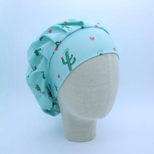 May include: A light blue scrub hat with a cactus and heart print. The hat is made of a soft, comfortable fabric and is perfect for nurses, doctors, and other healthcare professionals.