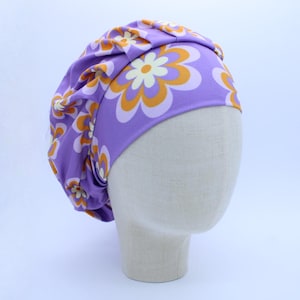 May include: Purple satin sleep cap with a retro floral print featuring orange and white flowers.