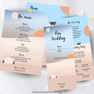 May include: Wedding stationery set featuring a desert landscape design with a blue sky and a setting sun. The set includes menus and wedding ceremony details. The color palette includes shades of blue, peach, and beige.