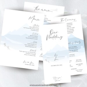 May include: A set of wedding stationery, including a menu and ceremony details cards. The cards have a white background with a light blue mountain design and elegant script. The wedding date is October 25, 2025.