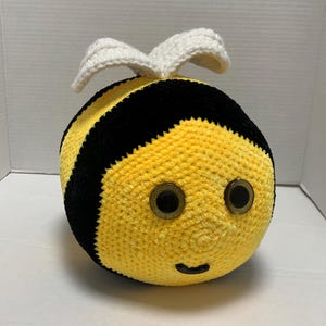 May include: A crocheted bee plush toy with black and yellow stripes, white wings, and black eyes.
