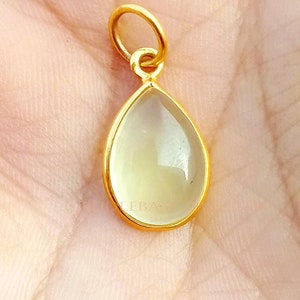 May include: A gold teardrop pendant with a clear, faceted gemstone.