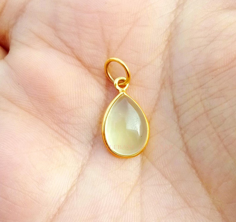 May include: A gold teardrop pendant with a clear, faceted gemstone.