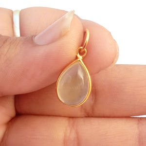 May include: A gold pendant with a clear teardrop-shaped gemstone.