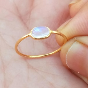 Könnte beinhalten: Ein goldener Ring mit einem ovalen Mondstein.