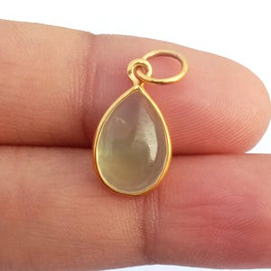 May include: A gold pendant with a teardrop-shaped clear gemstone.