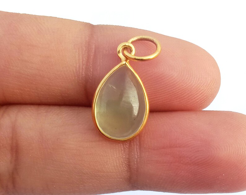 May include: A gold pendant with a teardrop-shaped clear gemstone.