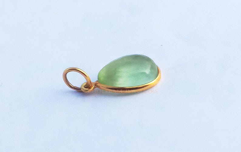 May include: A teardrop-shaped green gemstone pendant with a gold setting.