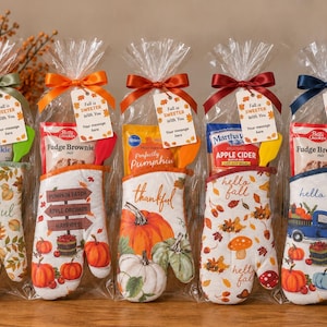 May include: Five clear cellophane gift bags containing baking mixes, silicone spatulas, and oven mitts with autumn-themed patterns. Each bag is tied with a satin ribbon and a tag that reads Fall is SWEETER With You and Your message here.