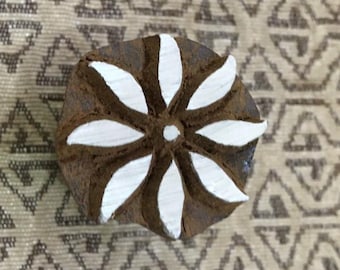 Peut inclure: Un tampon d'impression en bois avec un motif de fleur blanche. La fleur a six pétales et un petit cercle au centre.