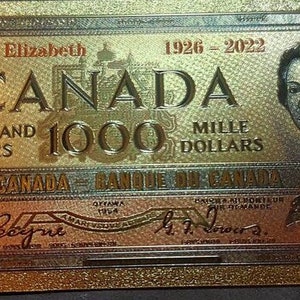 May include: A gold-coloured replica of a Canadian $1000 bill featuring Queen Elizabeth II and the text "Queen Elizabeth 1926-2022 CANADA ONE THOUSAND 1000 DOLLARS MILLE DOLLARS BANK OF CANADA - BANQUE DU CANADA"