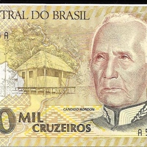 Op de afbeelding: Een bankbiljet van 1000 cruzeiros uit Brazilië met een portret van Candido Rondon, een Braziliaanse ontdekkingsreiziger en militair. Het bankbiljet toont ook een klein houten huis en de tekst "Banco Central do Brasil".
