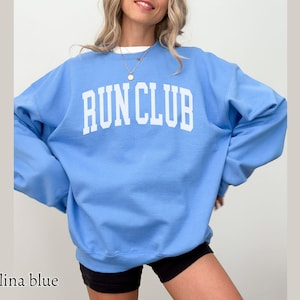 May include: A light blue sweatshirt with the text "RUN CLUB" printed in white on the front.